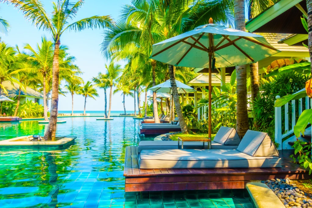 A luxurious Brazilian villa nestled amidst lush tropical foliage, its terracotta roof and ornate balconies basking in the golden glow of the setting sun. Plush, inviting lounge chairs flank a shimmering infinity pool that seamlessly blends with the distant horizon. Elegant arched windows frame a cozy, candlelit interior, hinting at the romantic ambiance within. Billowing sheer curtains dance in the gentle breeze, creating an atmosphere of tranquil, secluded indulgence. Elegant, contemporary decor and lush, verdant landscaping evoke a sense of refined sophistication in this idyllic, couples-oriented retreat.